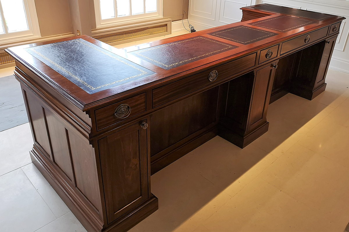 The Chewton Glen reception desk seen from its return end, showing the leather tops and moulded top edge