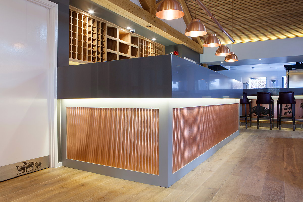 The fluted-copper bar and oak wine-rack back-bar of The Kitchen at Chewton Glen