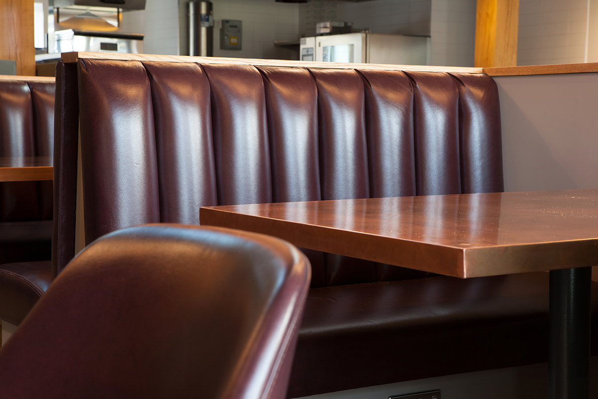 A leather booth with an oak capping and a copper-topped table at The Kitchen, Chewton Glen