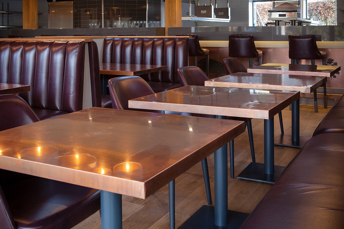 Copper-topped tables along the run of leather booths at The Kitchen, Chewton Glen