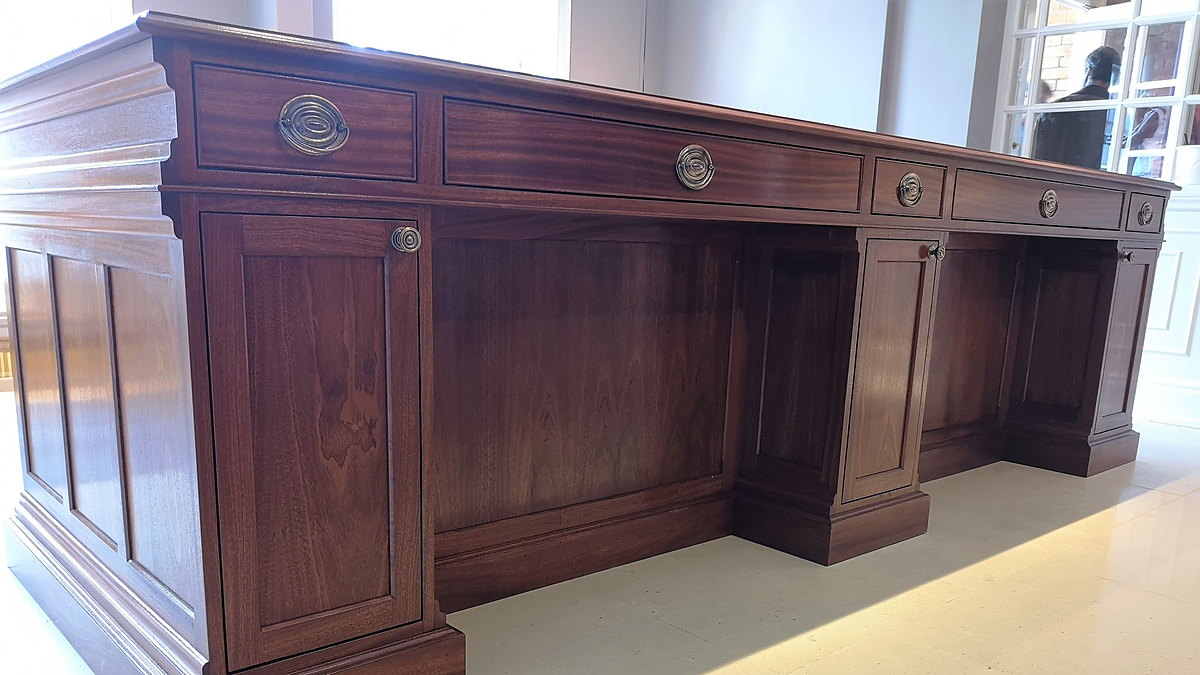 The front of the Chewton Glen reception desk: raised-and-fielded mahogany panels with inlaid stringing and brass ring pulls