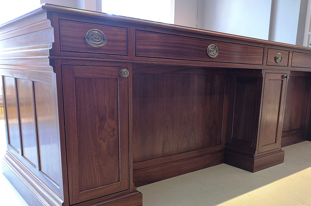 The front of the Chewton Glen reception desk: raised-and-fielded mahogany panels with inlaid stringing and brass ring pulls