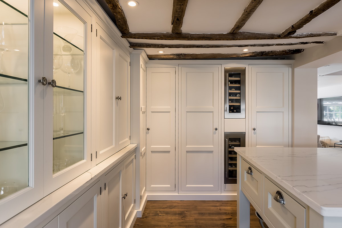 A glazed larder and dresser with a marble-topped island beneath original oak beams