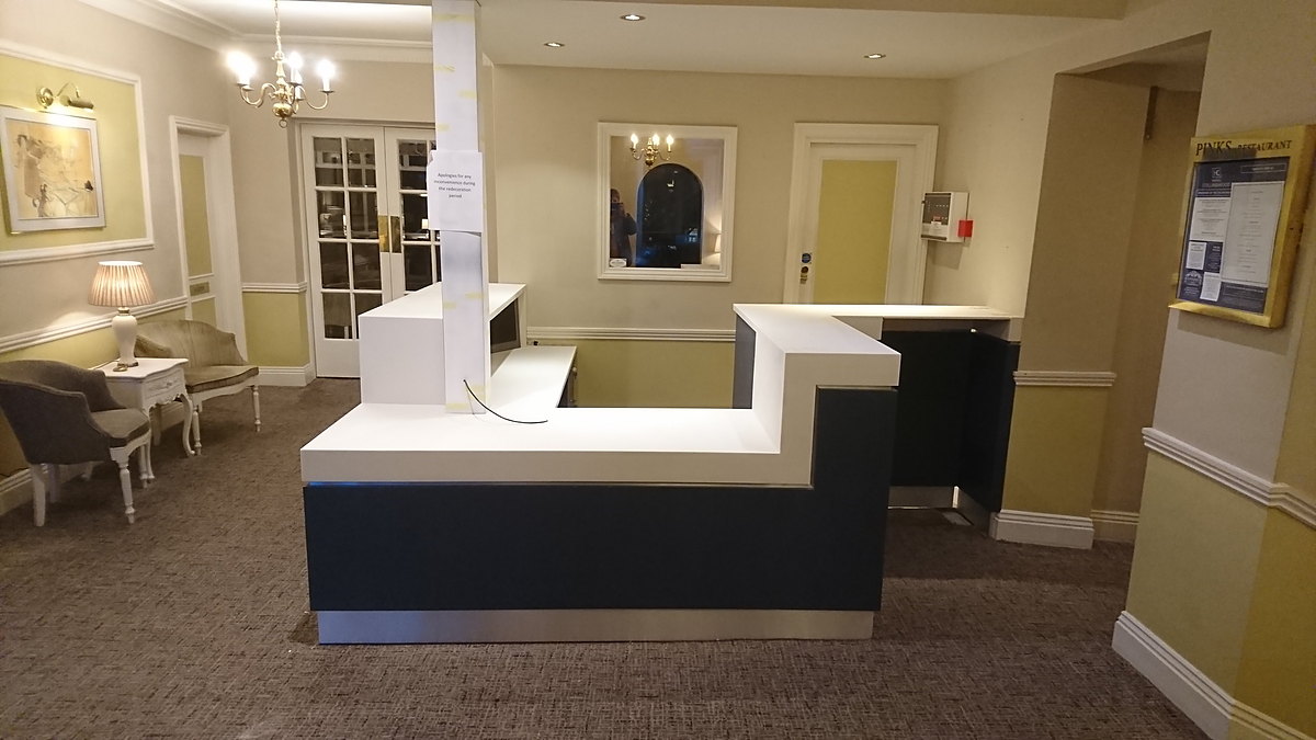 A hotel reception desk with a seamless Corian top over a painted front