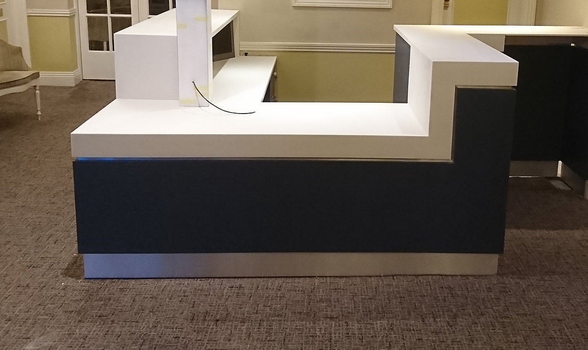 A hotel reception desk with a seamless solid-surface top over a dark painted front