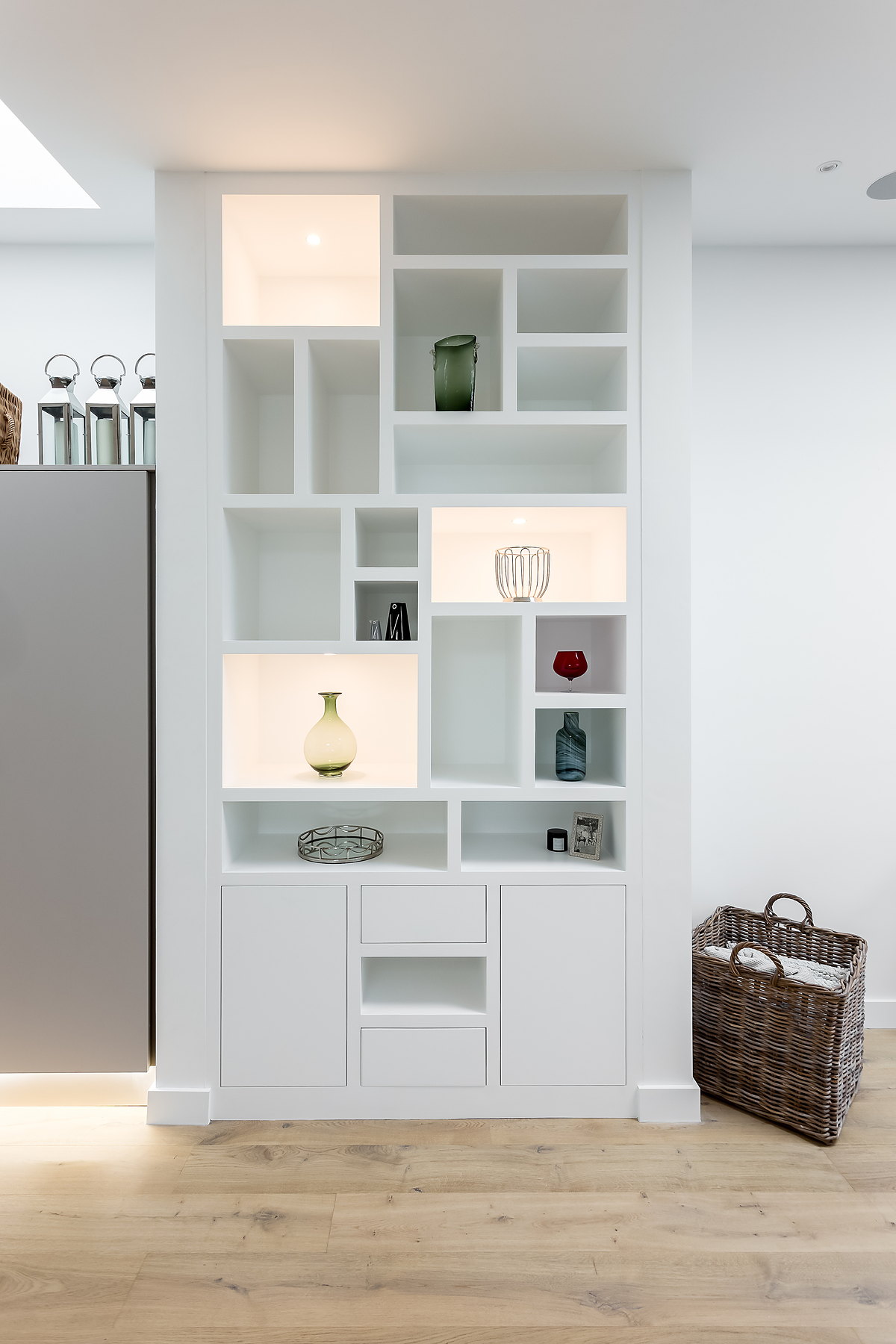 A painted fitted display unit with lit niches and cupboards beneath