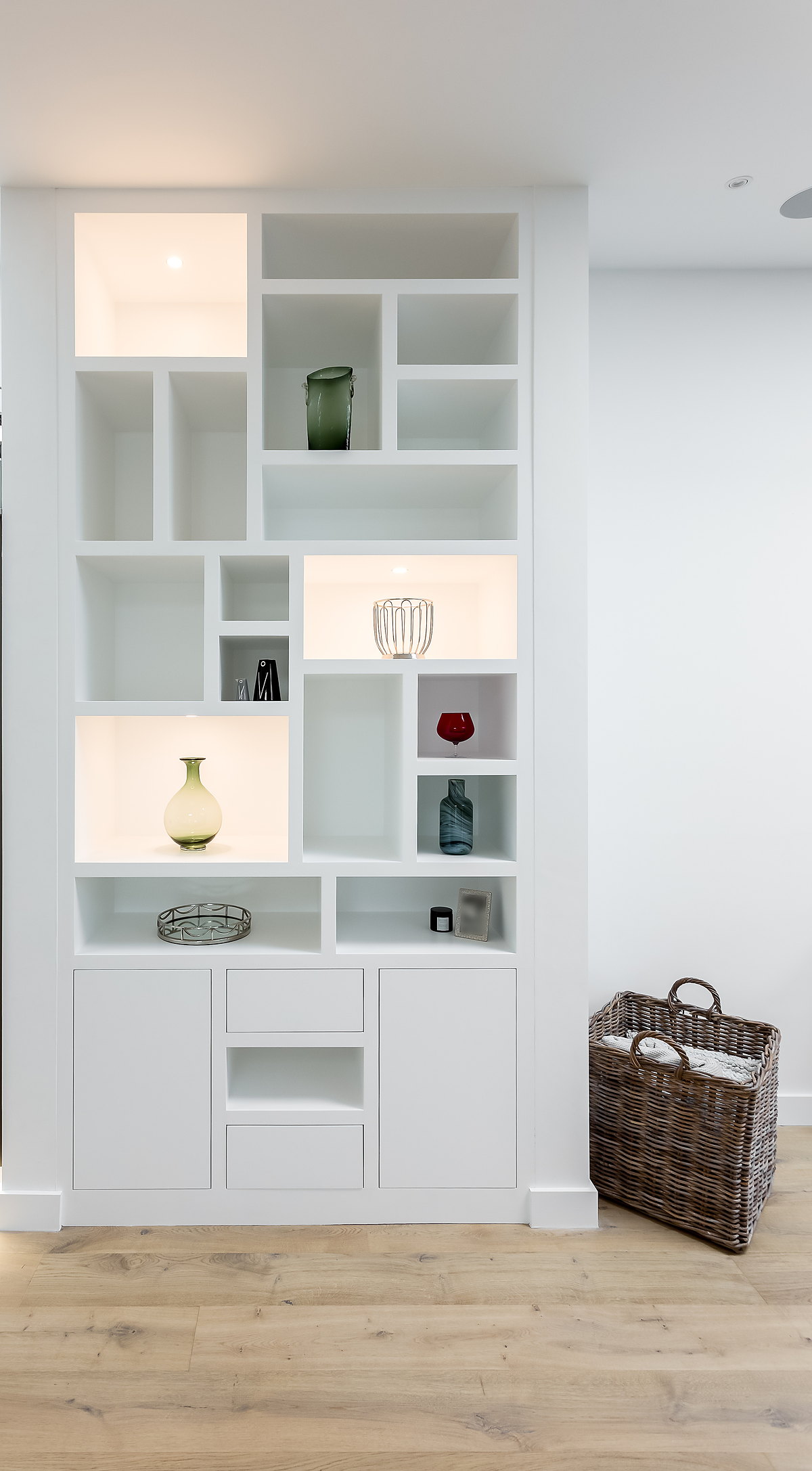 A painted fitted display unit with lit niches and cupboards beneath