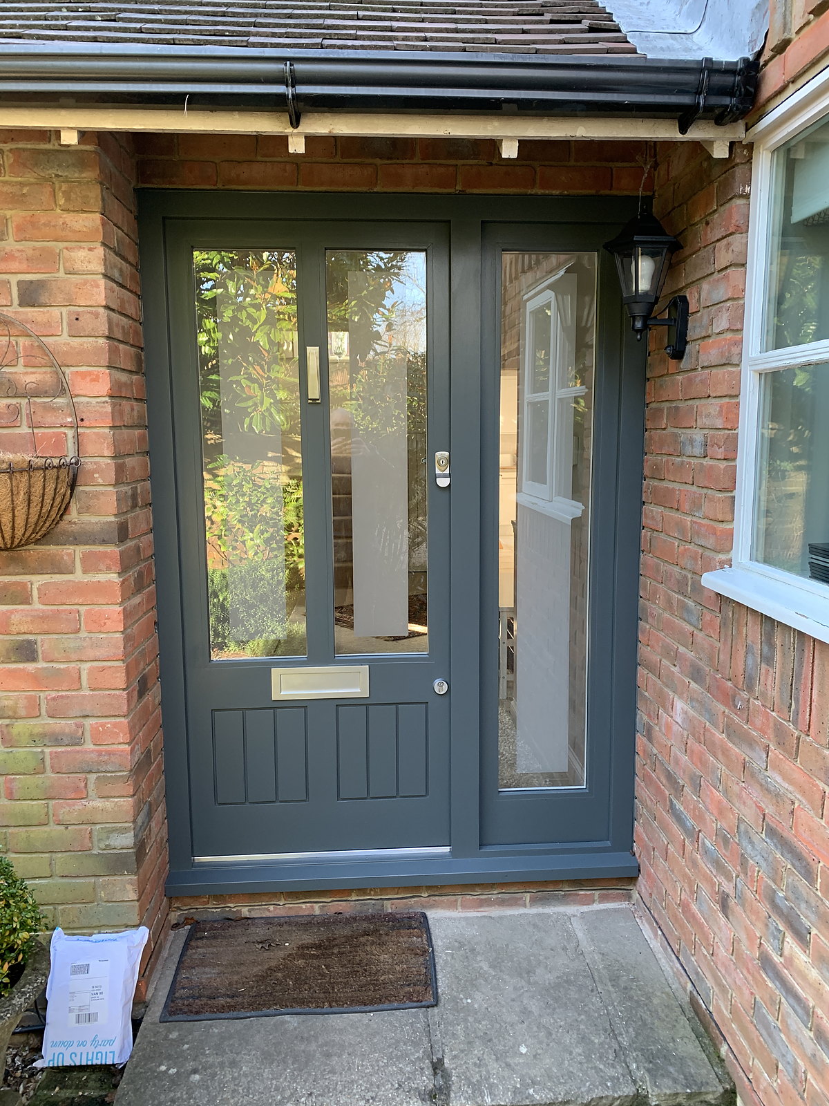A bespoke grey glazed timber entrance door in a brick surround