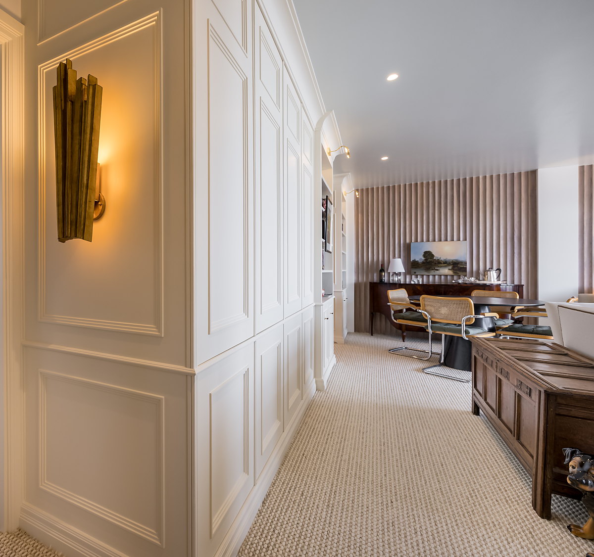 A hallway lined with painted full-height cupboards and matching wall panelling, finished with applied mouldings