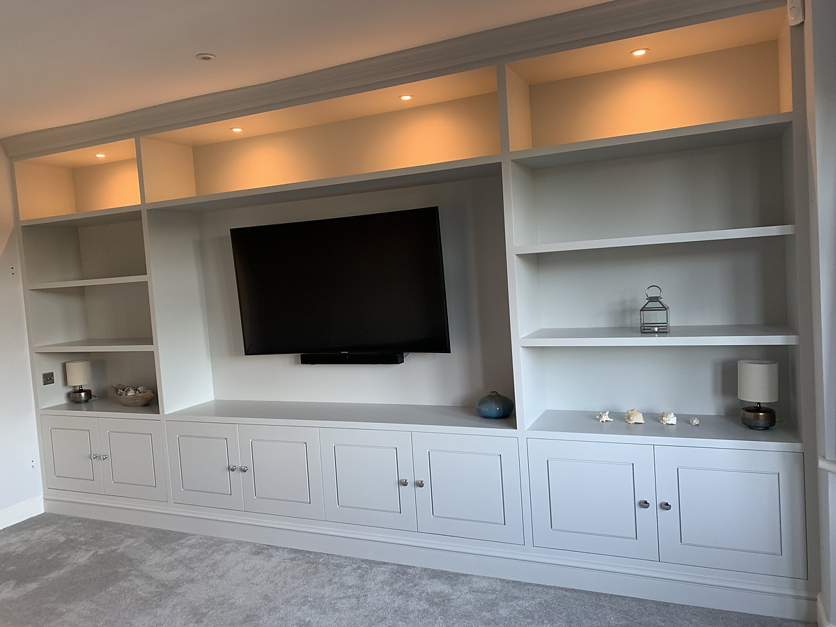 A bespoke media wall with fitted cabinets and open shelving