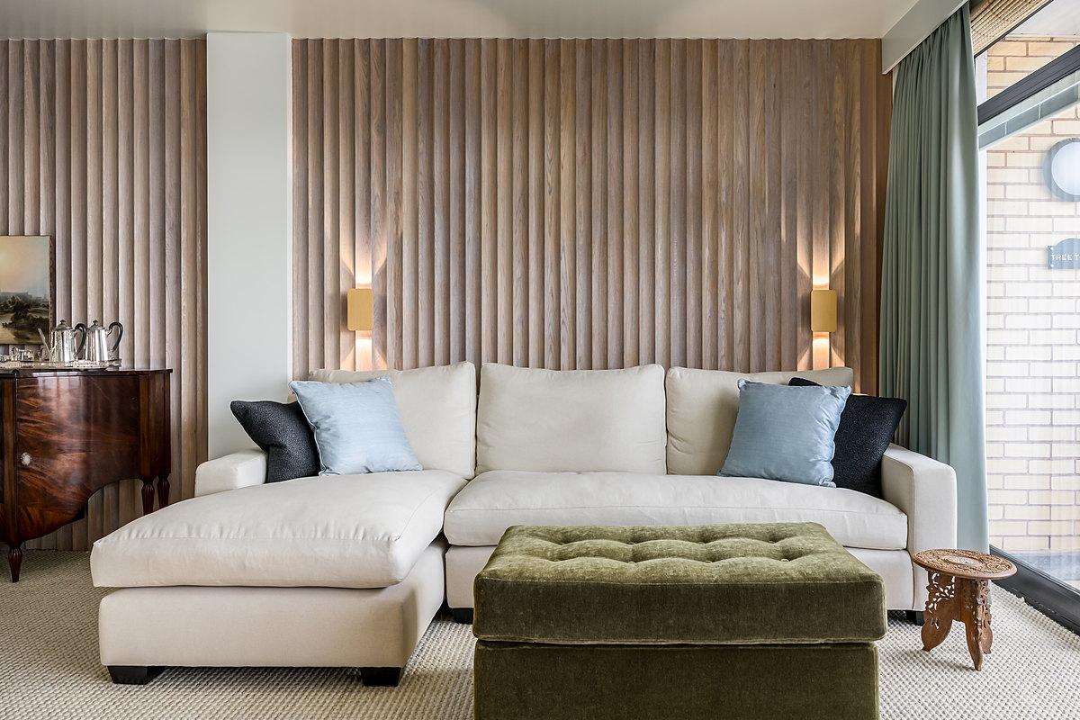A reeded and panelled drawing room with a fireplace and fitted seating