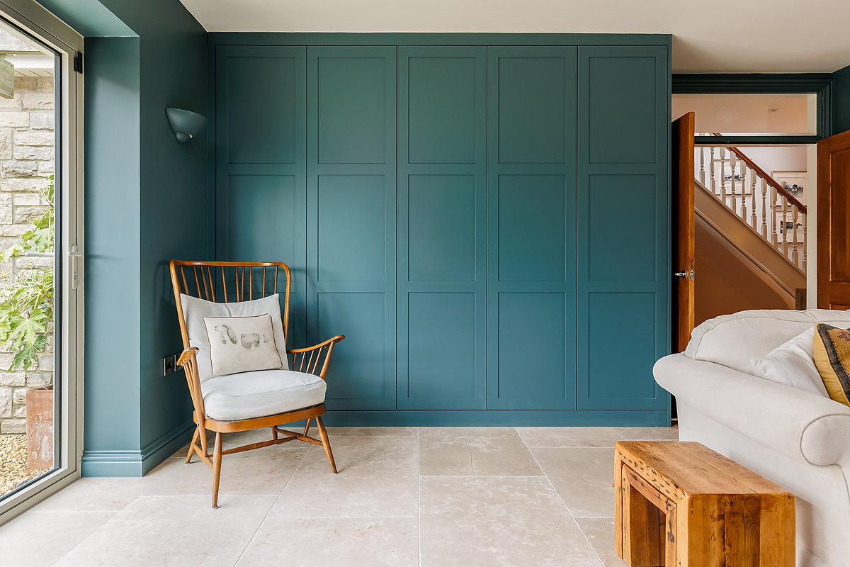 A panelled lounge wall in deep green, framing a fireplace and fitted joinery