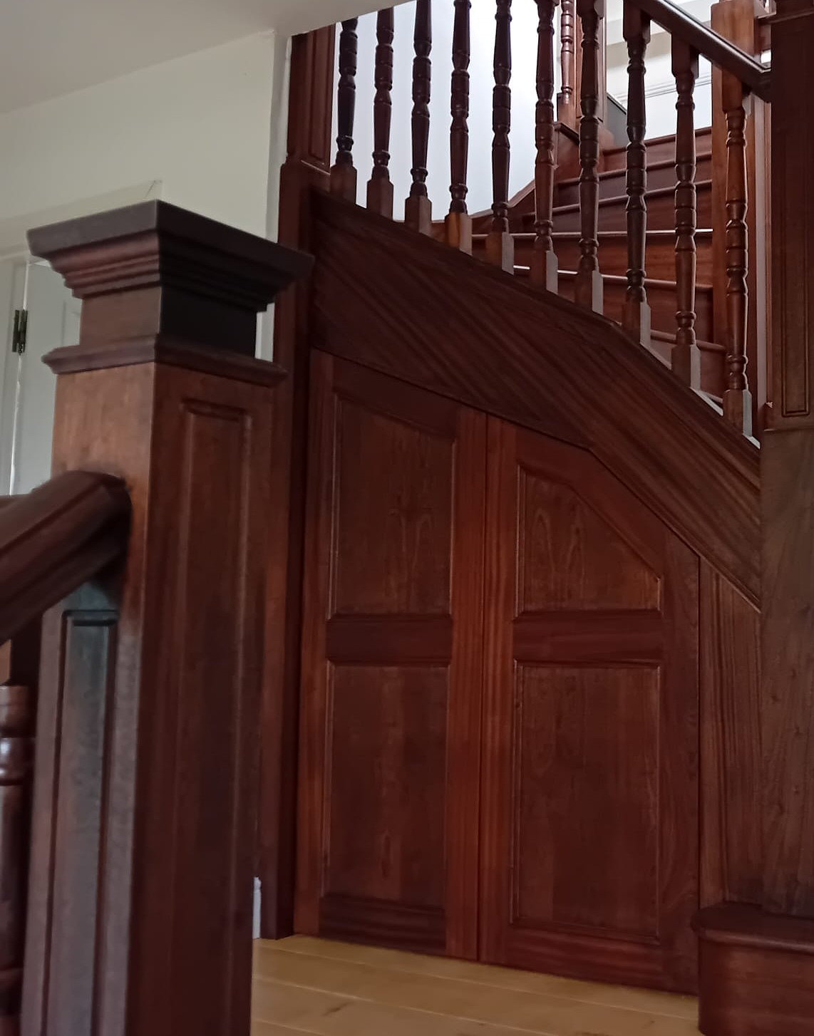 A mahogany balustrade of turned spindles and a panelled newel post on a galleried landing