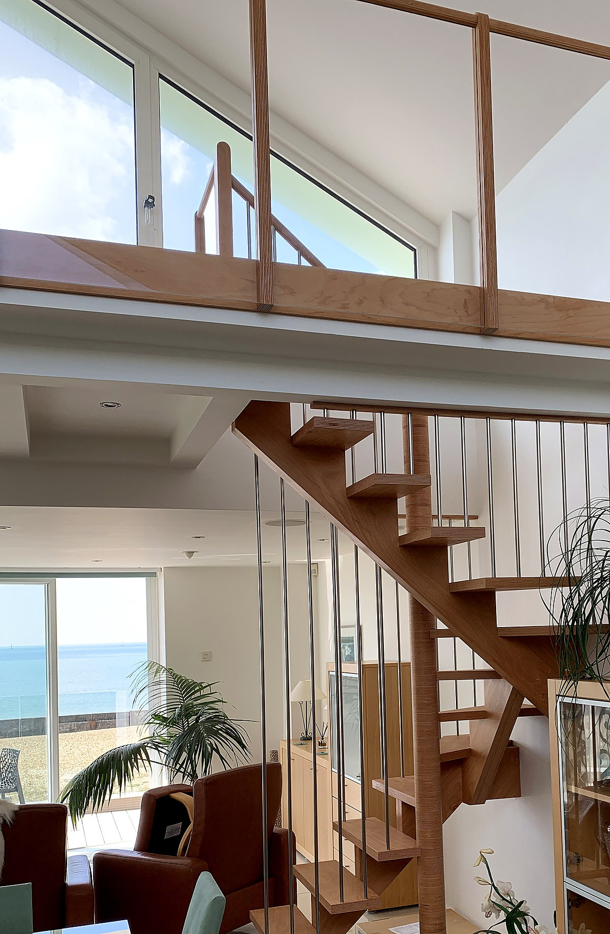 Bespoke oak open-tread staircase against a coastal window