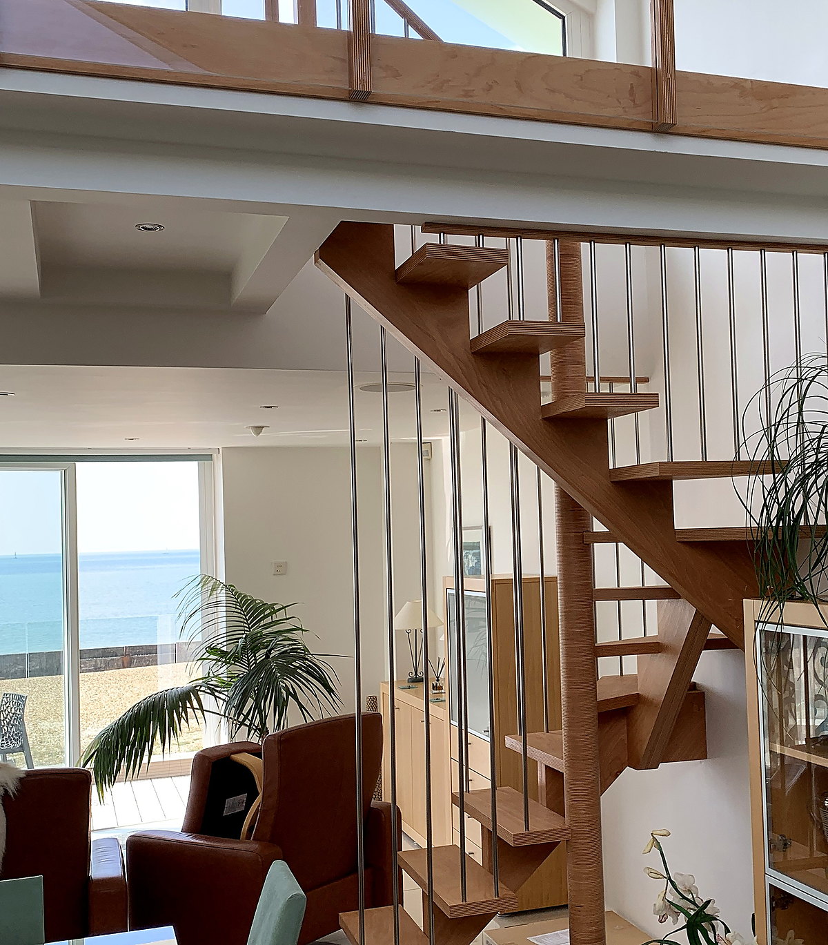 Bespoke oak open-tread staircase against a coastal window