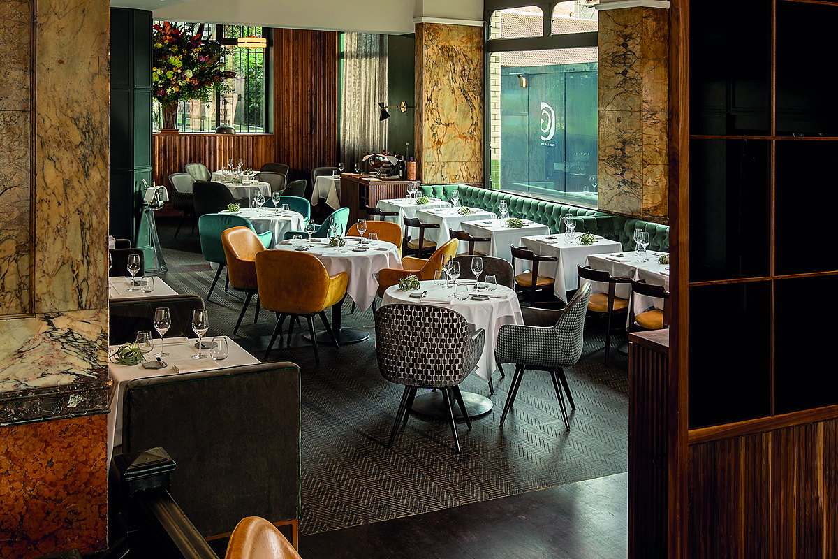 A fine-dining room with marble columns, walnut panelling and banquette seating