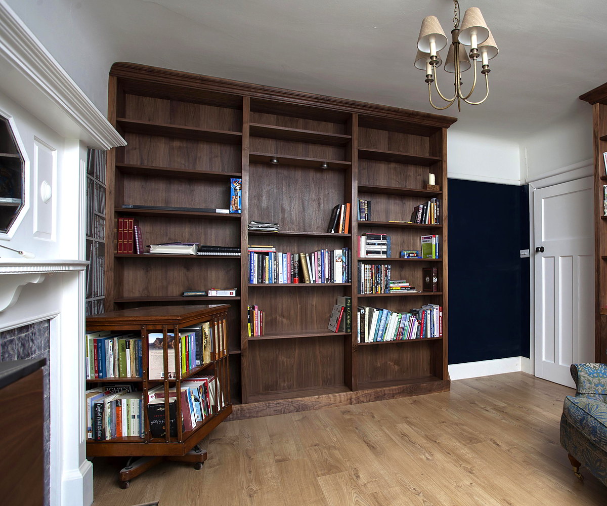 A walnut fitted library, floor to ceiling, beside a fireplace