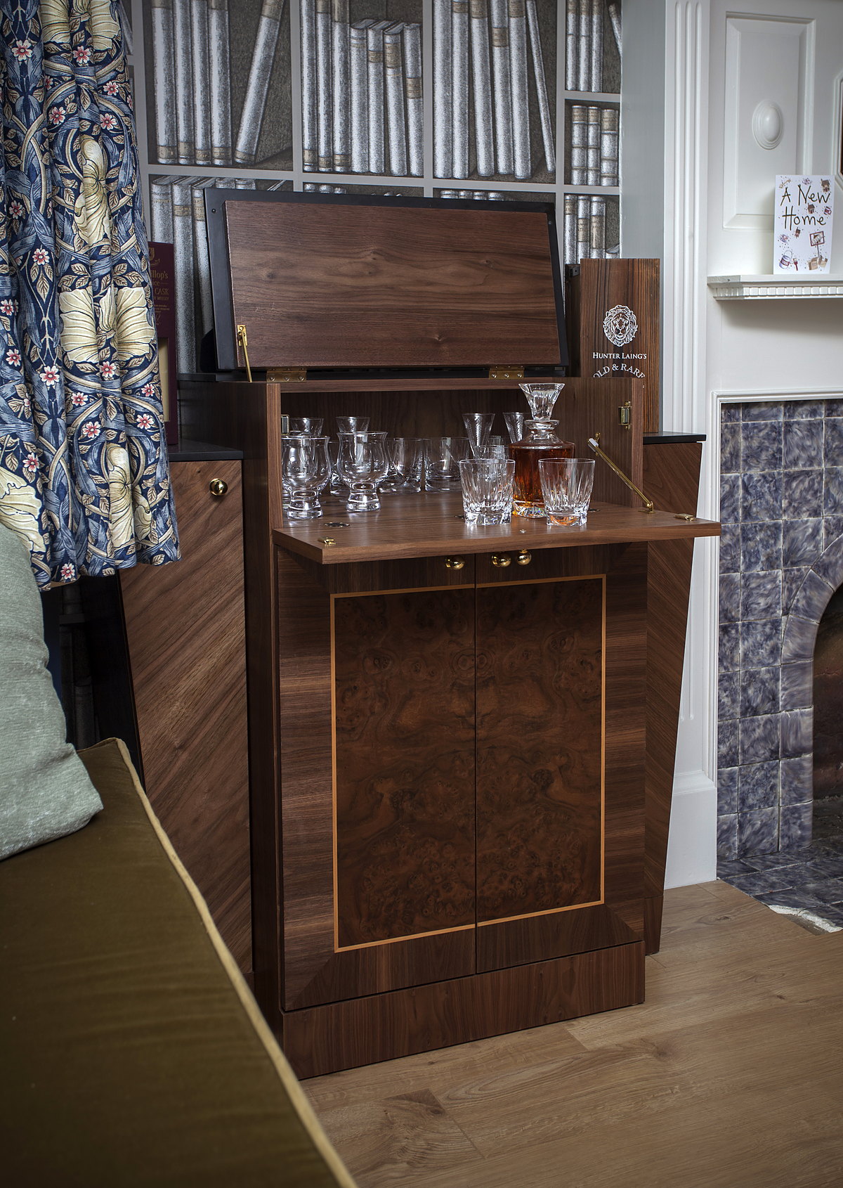 A bespoke burr-walnut drinks cabinet opening to a mirrored bar with decanters